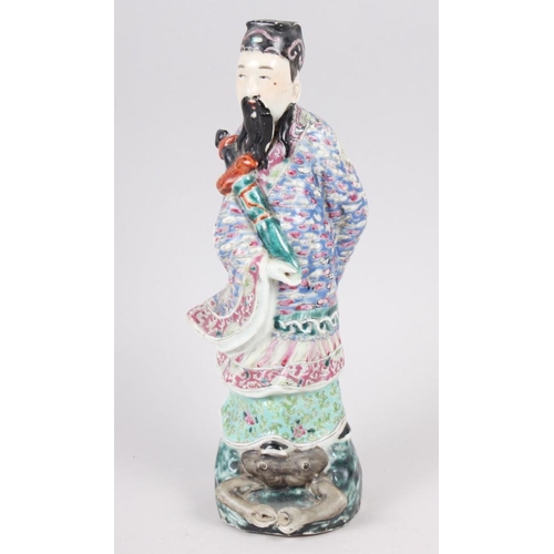 73 - A Chinese polychrome decorated figure of a man holding a sword, a green glazed wall pocket with reli... 