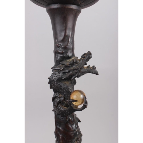 104 - A pair of Chinese bronze table lamps with relief dragon decoration, on circular bases, 17 1/2