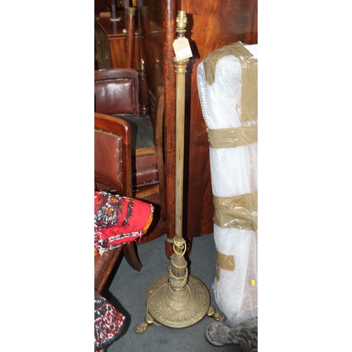 557 - A brass standard lamp with reeded column and three paw feet, 52