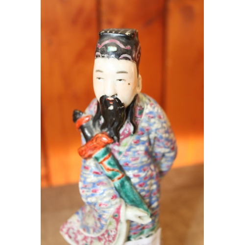 73 - A Chinese polychrome decorated figure of a man holding a sword, a green glazed wall pocket with reli... 