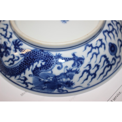 69 - Two Chinese blue and white dragon decorated dishes with six character marks to bases, similar plates... 