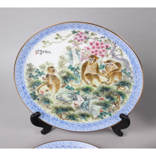 124 - A pair of Chinese plates, decorated monkeys in a landscape with character marks to base, 10 1/4