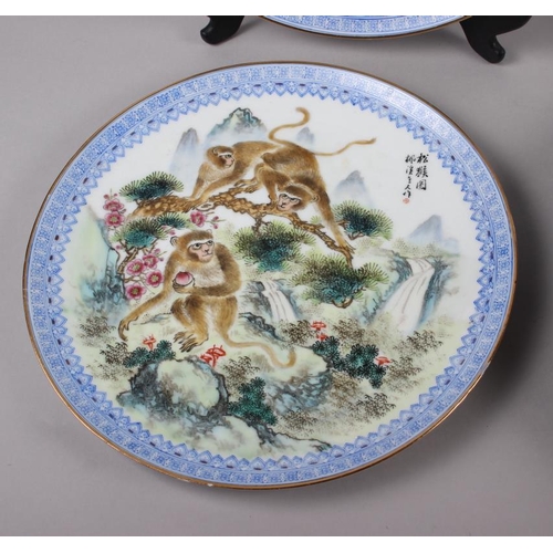 124 - A pair of Chinese plates, decorated monkeys in a landscape with character marks to base, 10 1/4