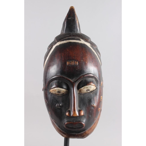 214 - A West African carved hardwood tribal mask, on ebonised stand, 22 1/2