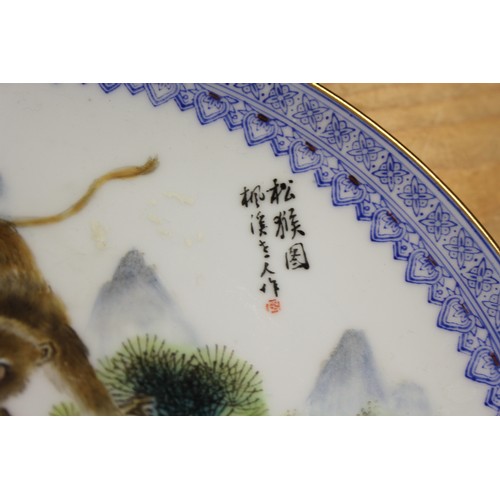 124 - A pair of Chinese plates, decorated monkeys in a landscape with character marks to base, 10 1/4