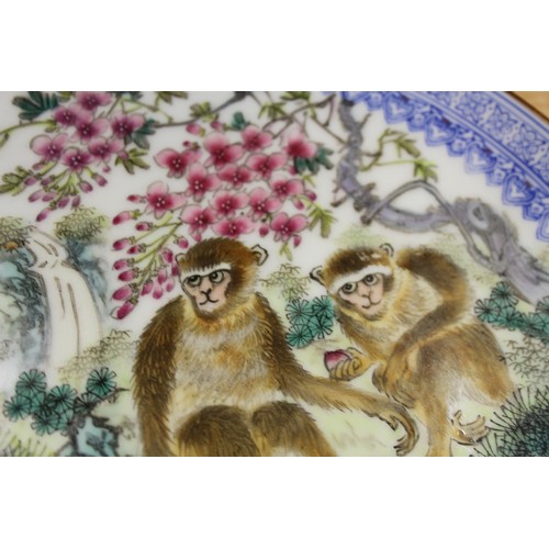 124 - A pair of Chinese plates, decorated monkeys in a landscape with character marks to base, 10 1/4