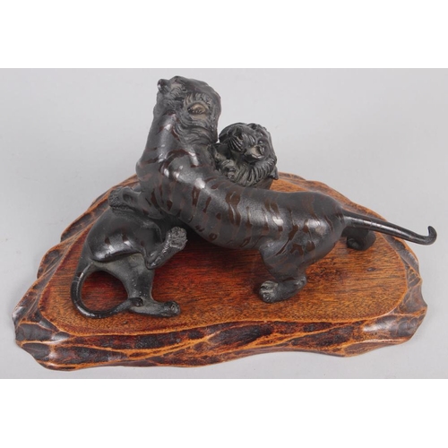 106 - A late 19th century Japanese bronze mode of two tigers fighting, on associated hardwood stand