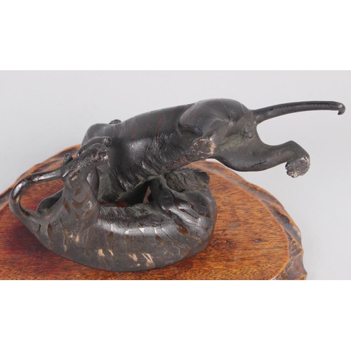 106 - A late 19th century Japanese bronze mode of two tigers fighting, on associated hardwood stand