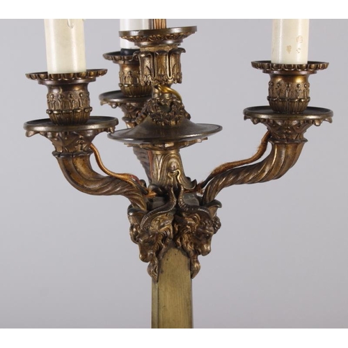 122 - A 19th century brass four light table candelabra with rams heads on triform base (now converted to e... 