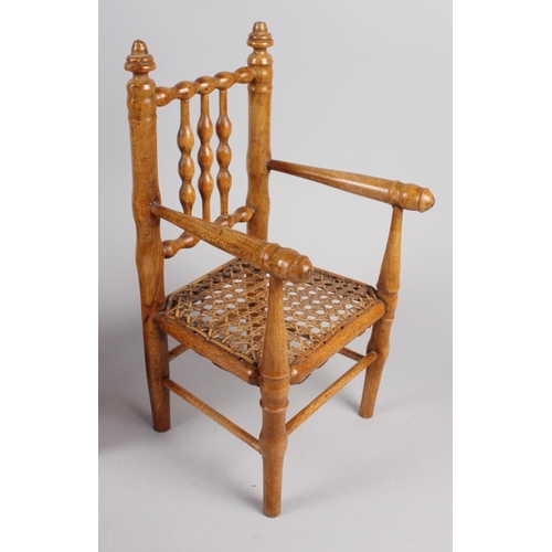 148 - A doll's turned wood spindle back chair with cane seat, 12