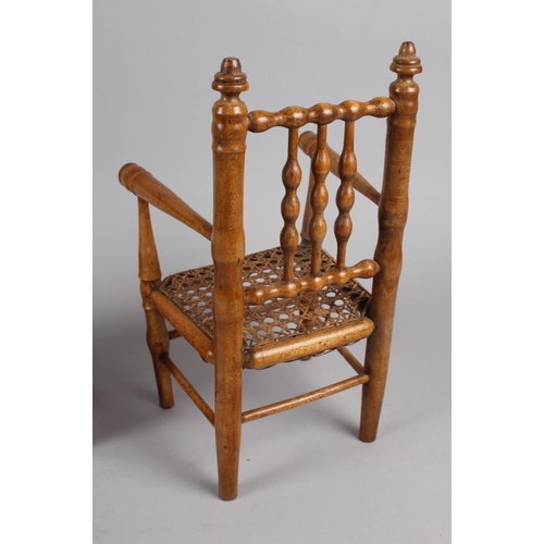 148 - A doll's turned wood spindle back chair with cane seat, 12