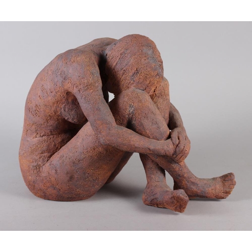 184 - A stoneware sculpture of a crouching nude figure, 11