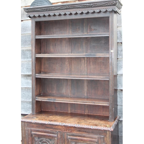 310 - A carved oak dresser, the upper section fitted four shelves over cupboard enclosed two panelled door... 