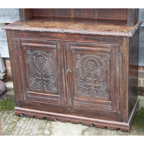 310 - A carved oak dresser, the upper section fitted four shelves over cupboard enclosed two panelled door... 