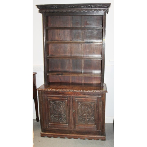 310 - A carved oak dresser, the upper section fitted four shelves over cupboard enclosed two panelled door... 