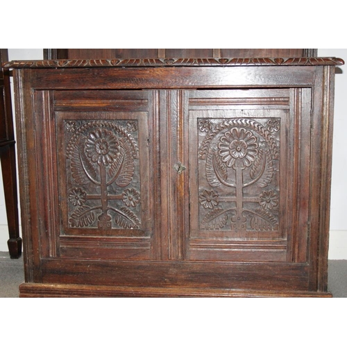 310 - A carved oak dresser, the upper section fitted four shelves over cupboard enclosed two panelled door... 