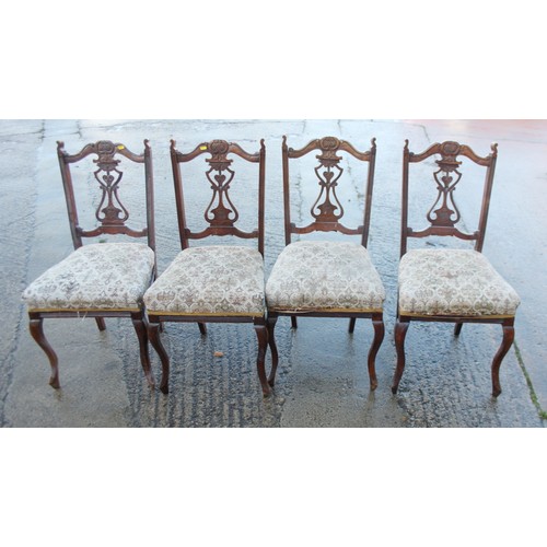 368 - A set of four carved walnut framed side chairs with pierced panel backs and stuffed over seats, on c... 