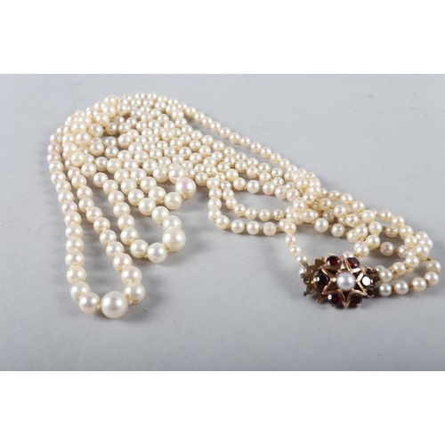 229 - A Mikimoto cultured pearl three-strand necklace with 9ct gold and garnet set star clasp, in case. 
T... 