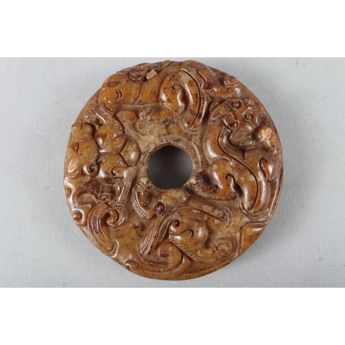 77 - A Chinese carved brown jade pi disc, 2 1/4