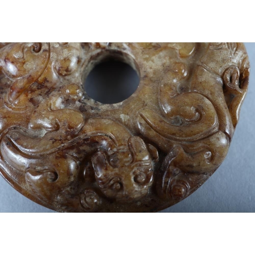 77 - A Chinese carved brown jade pi disc, 2 1/4