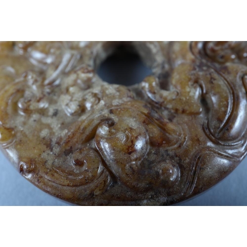 77 - A Chinese carved brown jade pi disc, 2 1/4