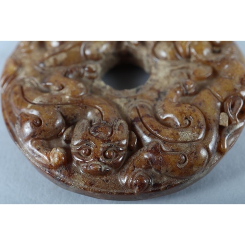 77 - A Chinese carved brown jade pi disc, 2 1/4