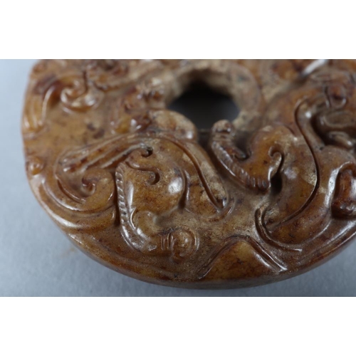 77 - A Chinese carved brown jade pi disc, 2 1/4