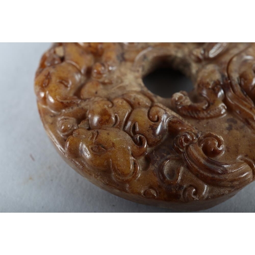 77 - A Chinese carved brown jade pi disc, 2 1/4