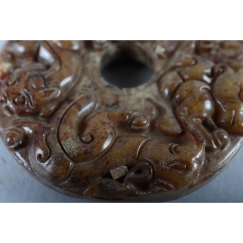 77 - A Chinese carved brown jade pi disc, 2 1/4