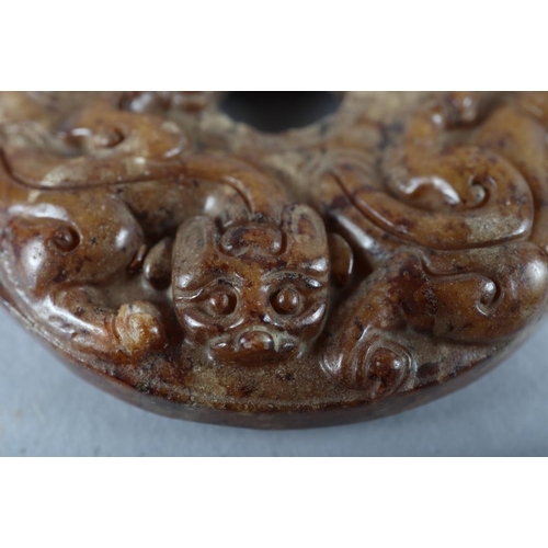 77 - A Chinese carved brown jade pi disc, 2 1/4