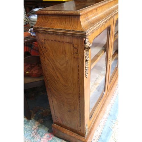 406 - A Victorian figured walnut gilt metal mounted low bookcase enclosed two glazed arch top doors, on bl... 