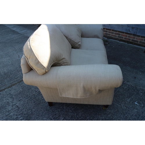 538 - A two-seat settee with splay arms and down loose seat and back cushions, on turned supports and bras... 