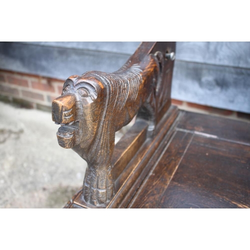 583 - A monk's carved oak bench with box seat and lion arms, 42 1/2