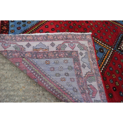 606 - A Persian woven village rug of traditional design on a red ground, 78