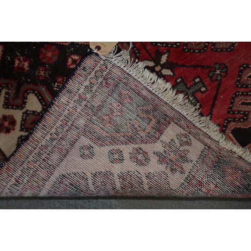 618 - A Qashqai rug with three red medallions on a dark floral ground, 60