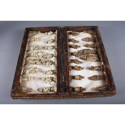 255 - An Aztec inspired composite chess set, in folding oak case