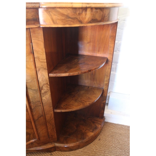 427 - A late Victorian figured walnut shape front credenza with open shelves and panel bowfront door, on b... 