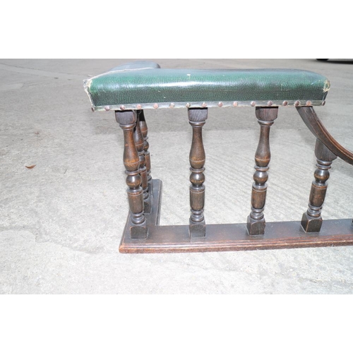 588 - An early 20th century oak club fender, upholstered in a green leather, over turned supports, 66