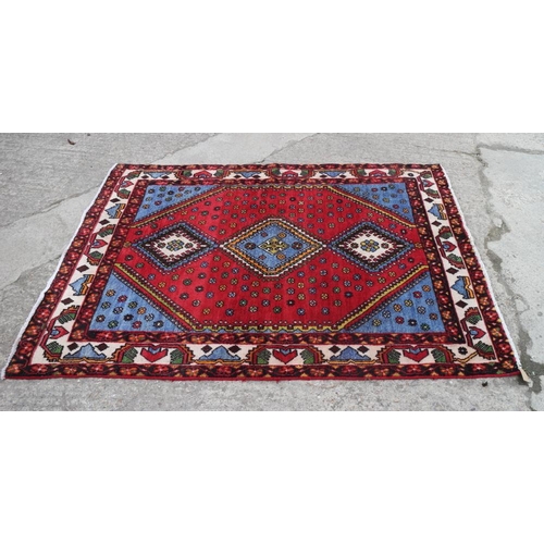 606 - A Persian woven village rug of traditional design on a red ground, 78