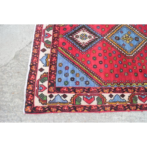 606 - A Persian woven village rug of traditional design on a red ground, 78