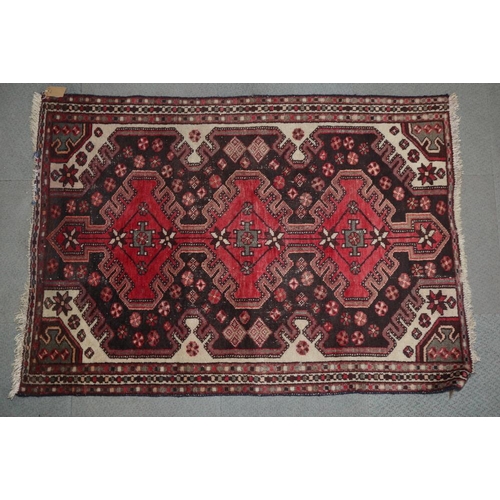 618 - A Qashqai rug with three red medallions on a dark floral ground, 60