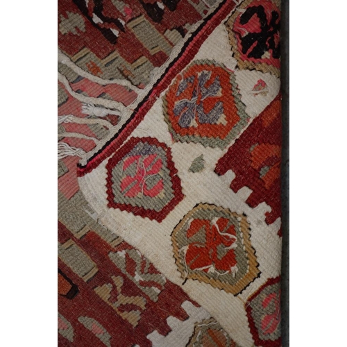 619 - A kelim rug with three medallions on a salmon ground and single border in shades of red brown and na... 