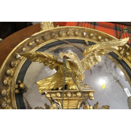 509 - A circular giltwood wall mirror with eagle finial and carved balls flanked by candleholders (now con... 