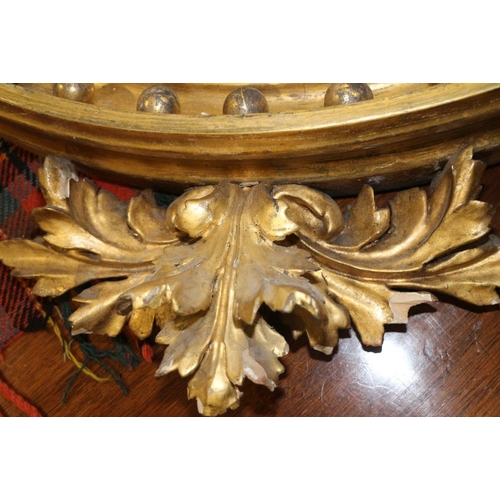 509 - A circular giltwood wall mirror with eagle finial and carved balls flanked by candleholders (now con... 