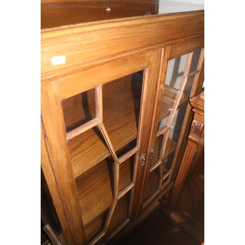 568 - An oak ledge back display cabinet, enclosed lattice glazed doors, on turned and stretchered supports... 