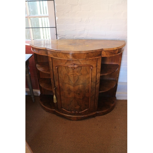 389 - A late Victorian figured walnut shape front credenza with open shelves and panel bowfront door, on b... 