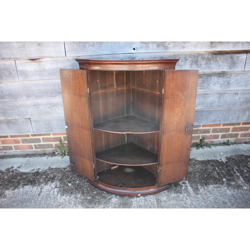 389 - A Georgian mahogany bowfront corner hanging cupboard enclosed two doors, 28