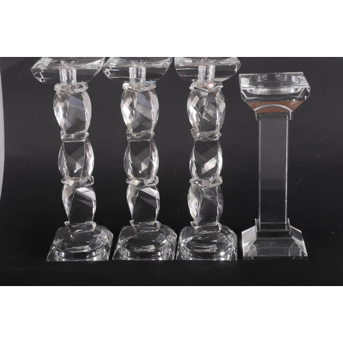 48 - A set of three Kenneth Turner glass candlesticks, on facet cut stems, and another plain square-secti... 