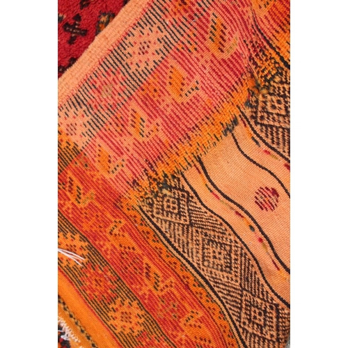 518 - A flat weave and pile rug with three panels on an orange ground, 77