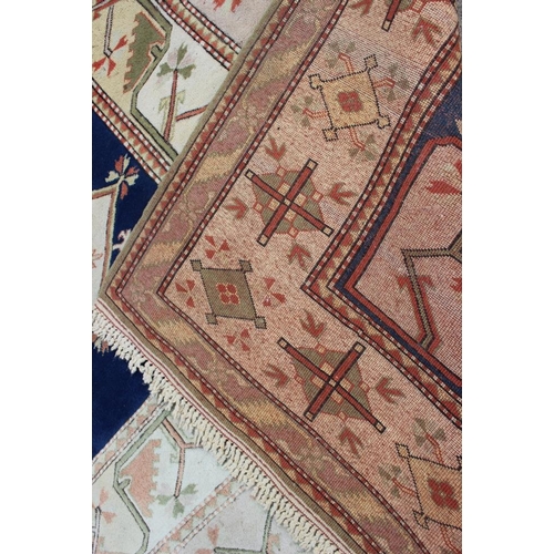 524 - A Caucasian wool pile carpet with central guls and geometric and floral designs, on a terracotta gro... 